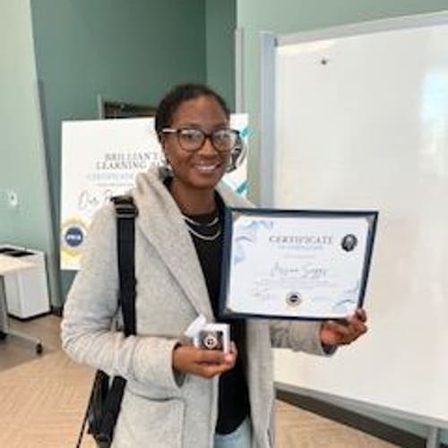 A Brilliantaires graduate holding her certificate